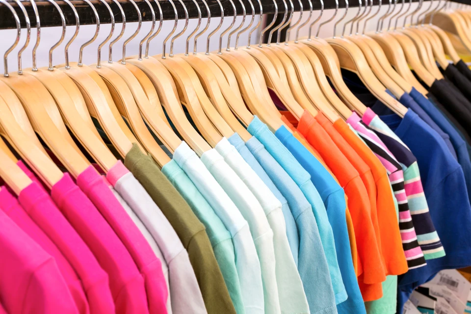 Intérieur de magasin de vêtements avec portant de vêtements colorés suspendus sur cintres en bois