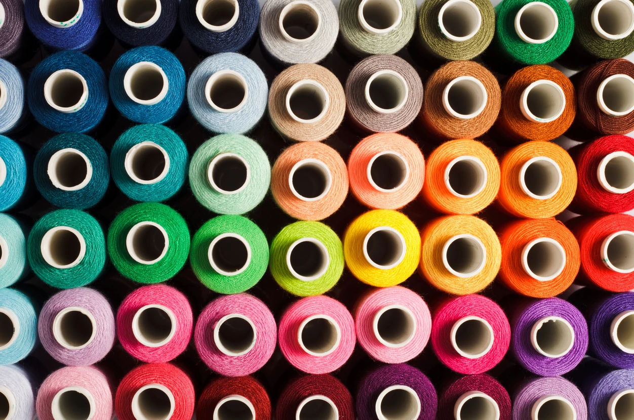 Fils de couture sur fond multicolore en gros plan