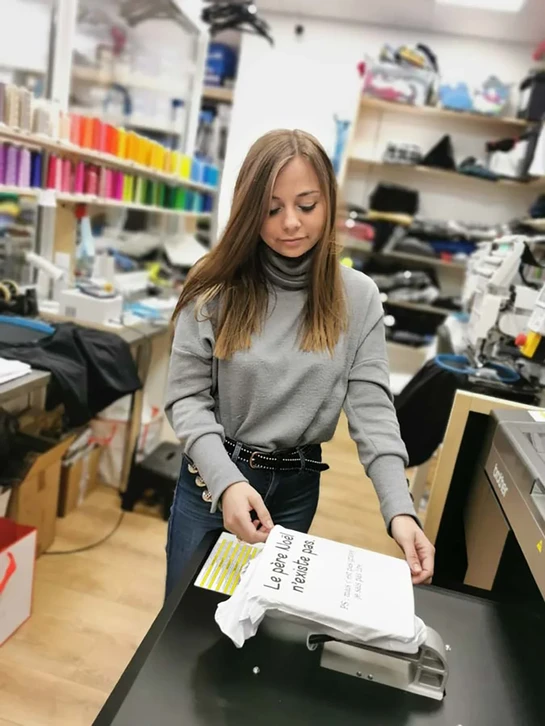 Femme artisane dans atelier lumineux, chemise à carreaux brune, expression concentrée et professionnelle